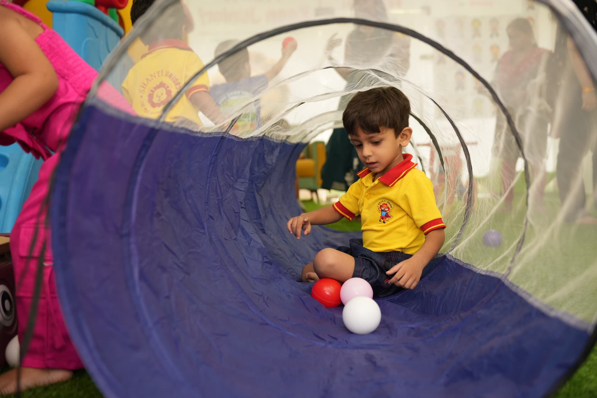 Toddler playing inside a soft play tunnel